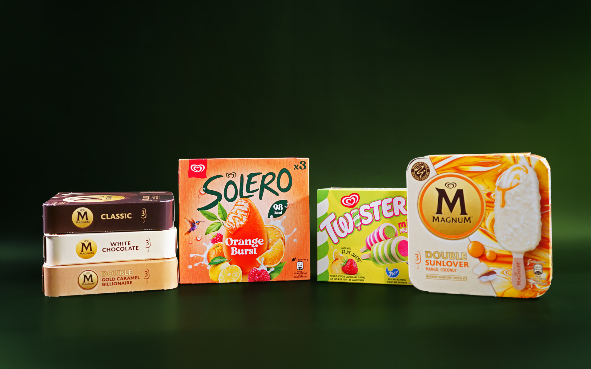 Multiple boxes of ice creams are lined up next to each other against a dark green background. There are six boxes in total, all of different flavours, including Magnum ice cream sticks, Solero and Twister.