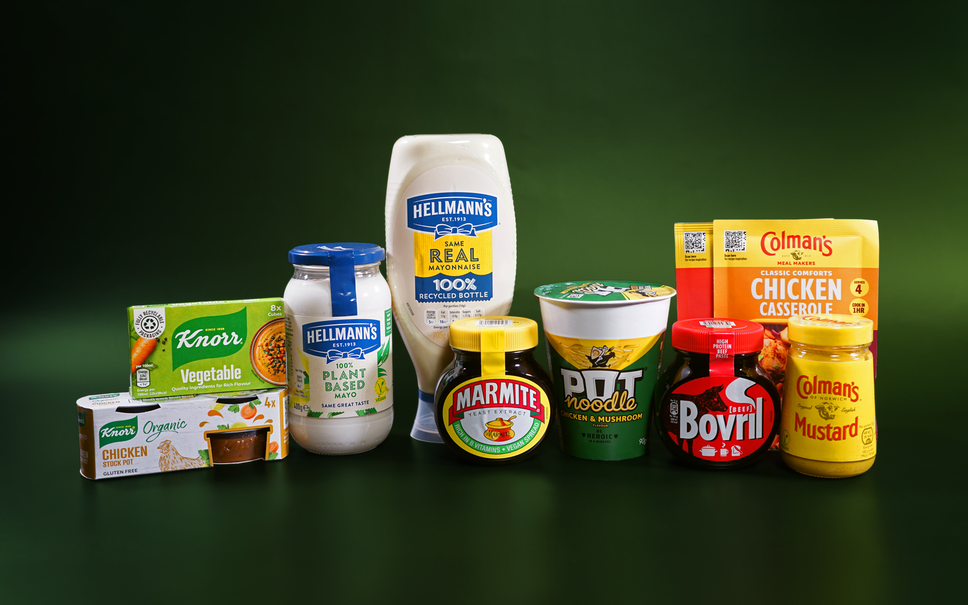 Various Unilever Foods products are lined up next to each other against a dark green background. These products include stock pots, stock cubes, mayonnaise, savoury spreads, instant noodles, recipe mixes and mustard. The brands visible include Knorr, Hellmann’s, Marmite, Pot Noodle, Bovril and Colman’s.